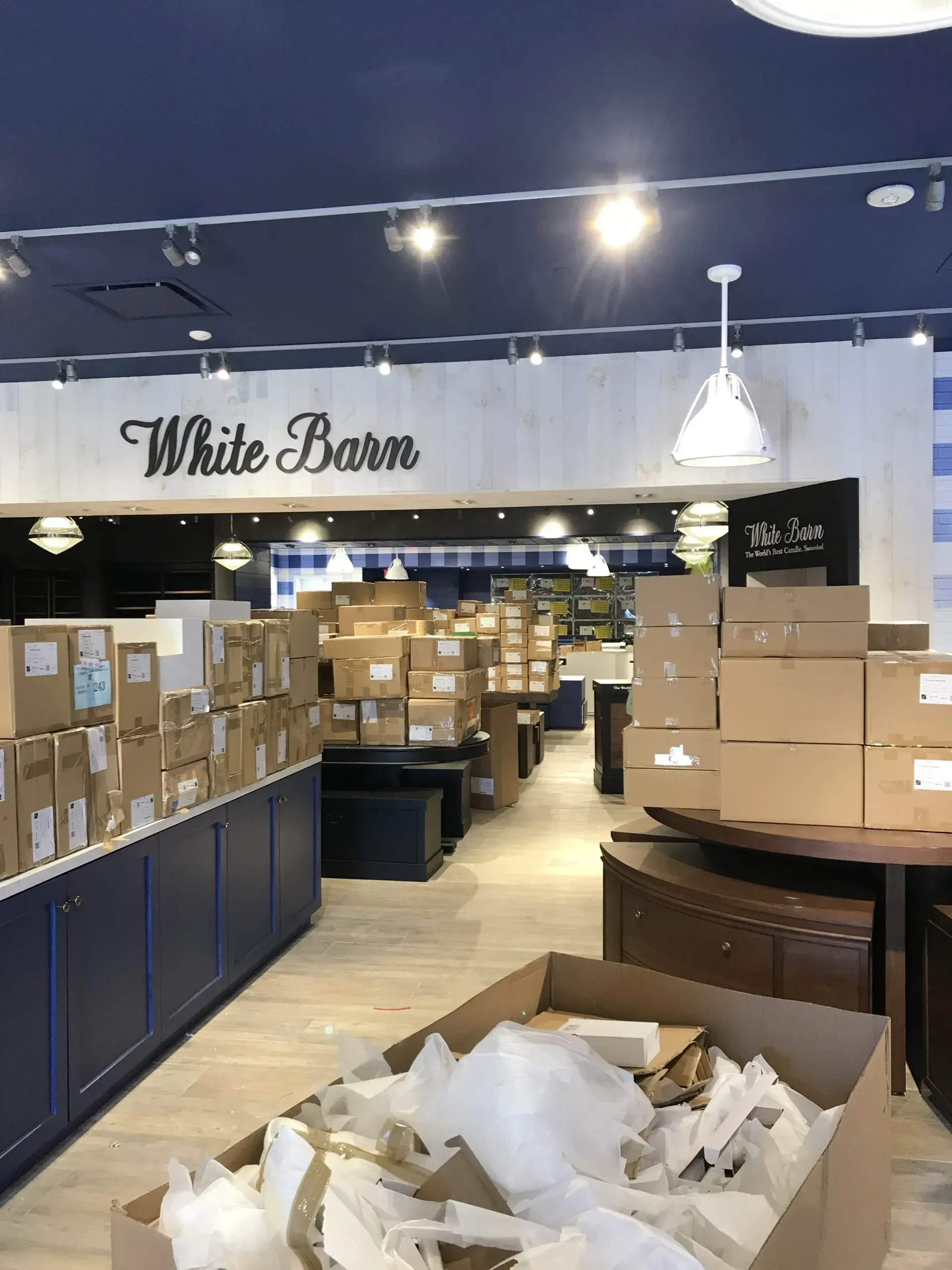 Interior of a White Barn store filled with boxes and packaging during setup.