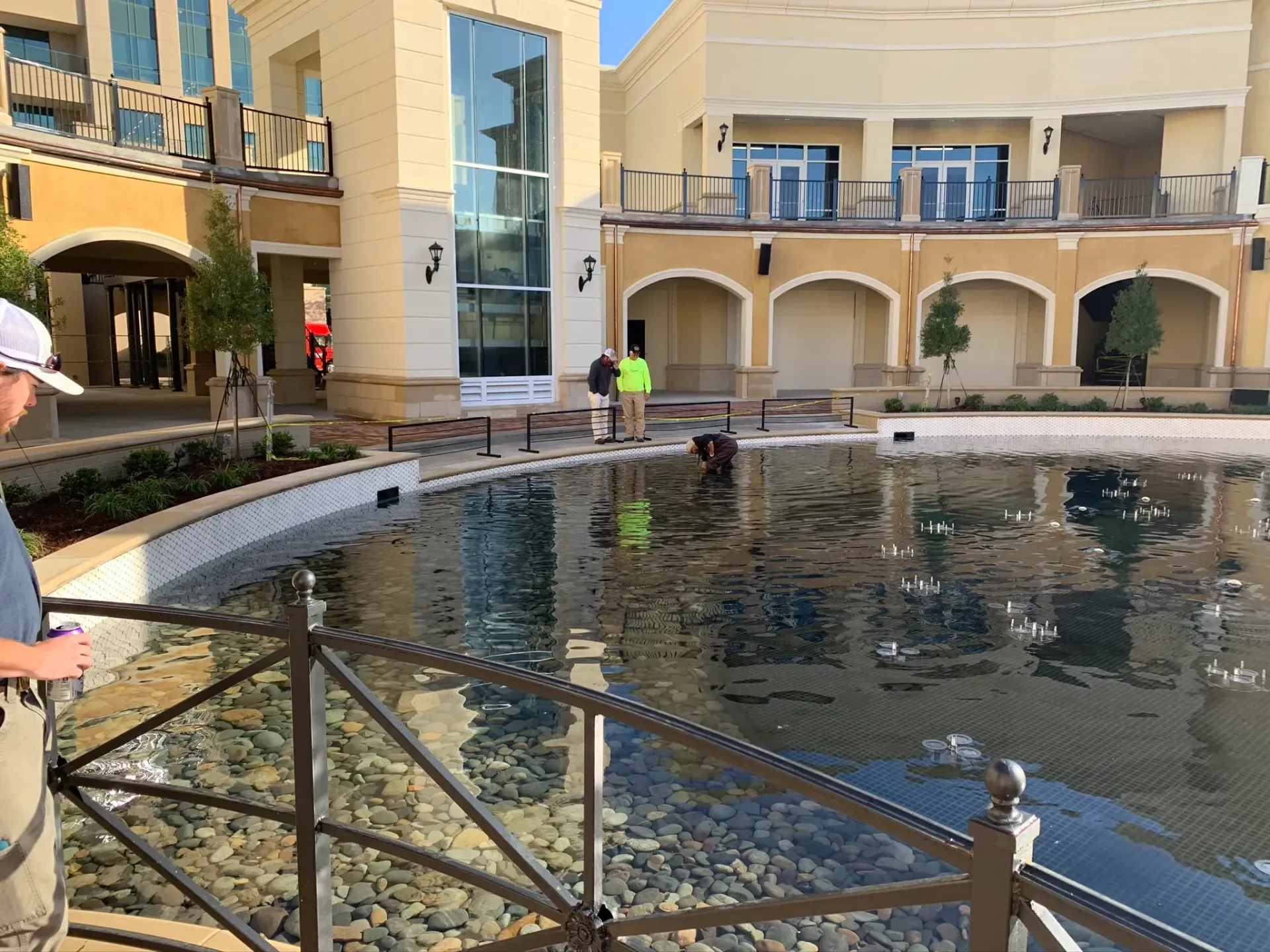 People near a water feature with buildings in the background. Sunny day.