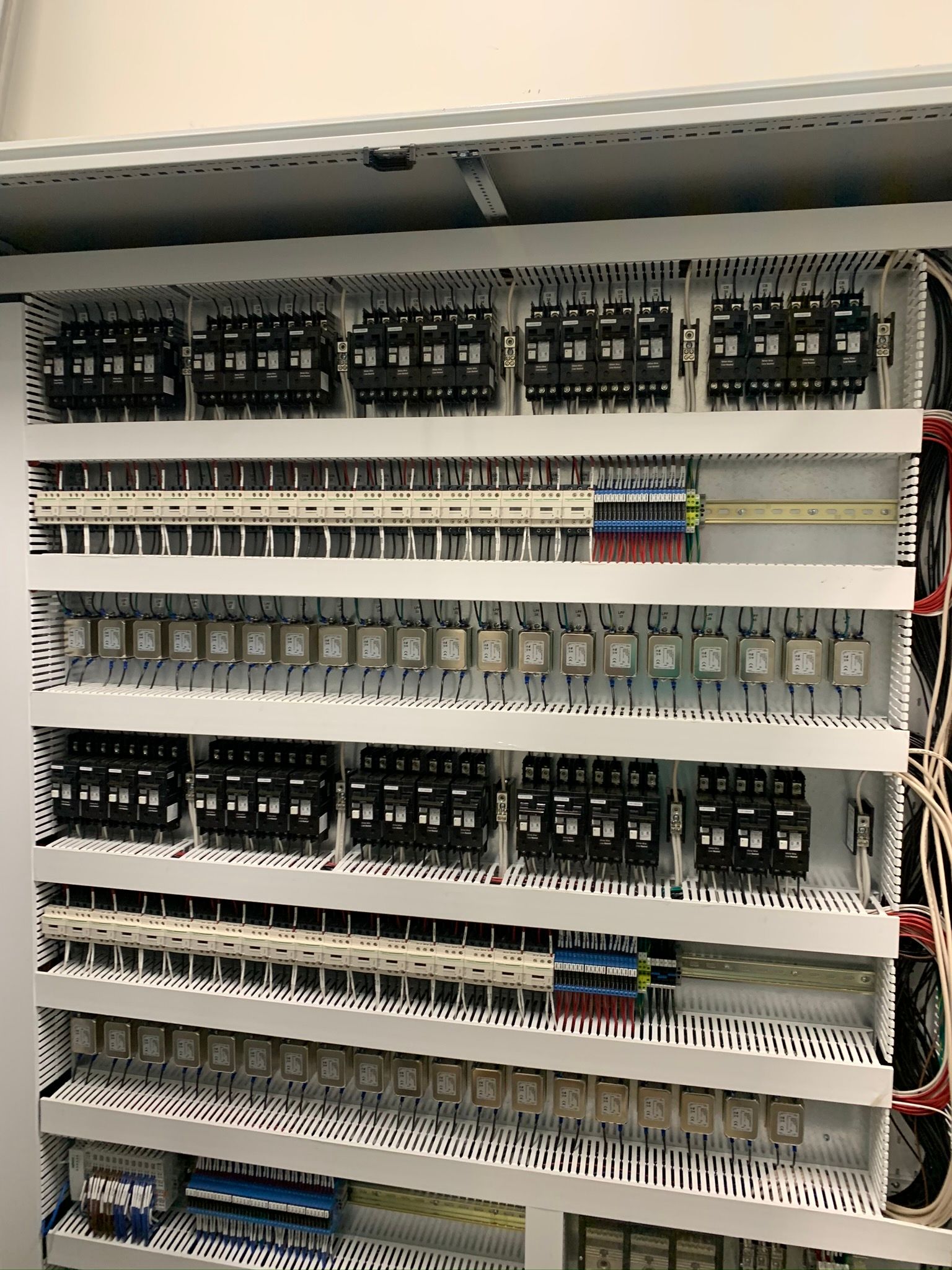 Electrical control panel with rows of circuit breakers, relays, and terminal blocks.