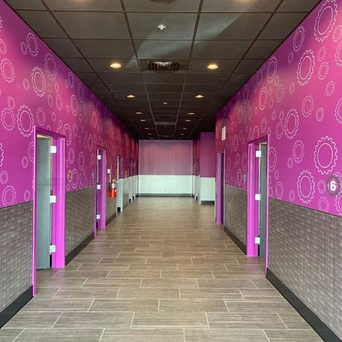 Hallway with pink and silver walls, gray tile floor, and black ceiling.
