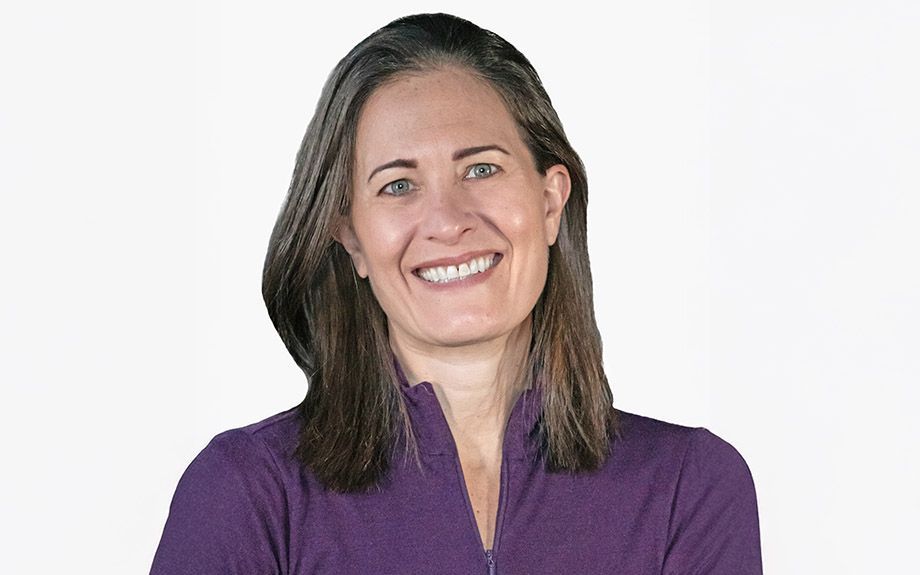 Woman in a purple shirt smiling, against a white background.