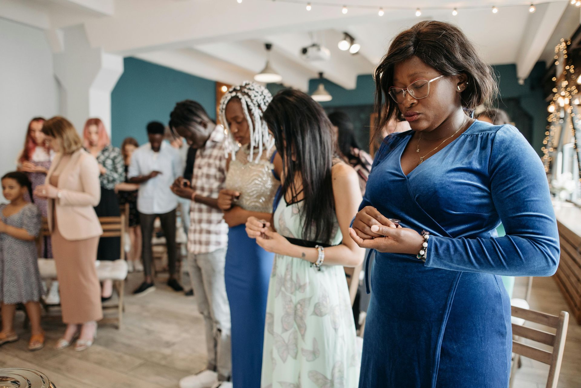 People praying with bowed heads indoors.