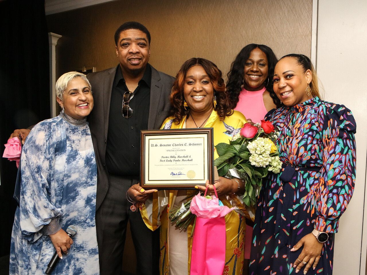 Photo of First Lady Paula Marshall holding an award with Senior Pastor Billy Marshall and some church members at Overflow Christian Center