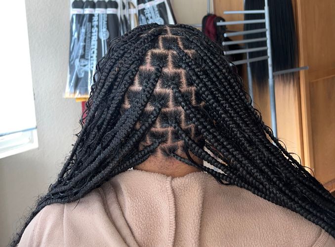 A woman with braids on her head is wearing a towel.