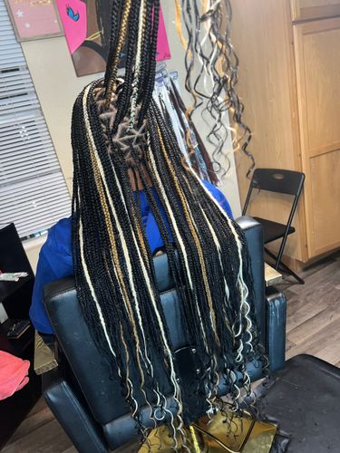 A woman is sitting in a chair with braids in her hair.