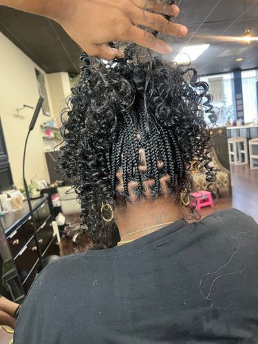 A woman is getting her hair braided in a salon.