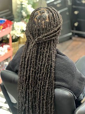 A woman with long dreadlocks is sitting in a chair in a salon.