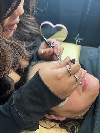 A woman is getting her eyelashes done by a makeup artist.