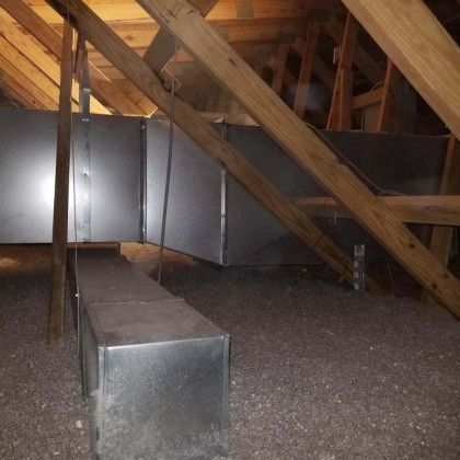 A metal box is sitting in the middle of a wooden attic.