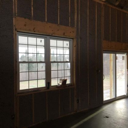 A room with two windows and a sliding glass door