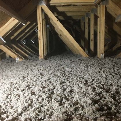 An attic with a lot of insulation and wooden beams