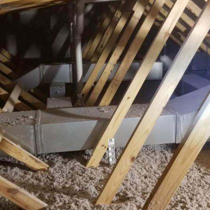 There is a duct in the attic of a house.