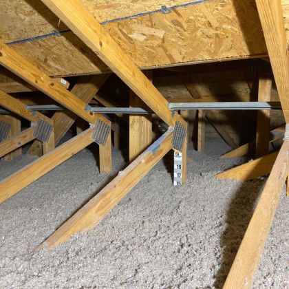 The attic of a house with wooden beams and insulation.