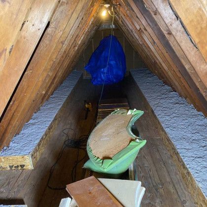 There is a blue bag hanging from the ceiling in the attic.