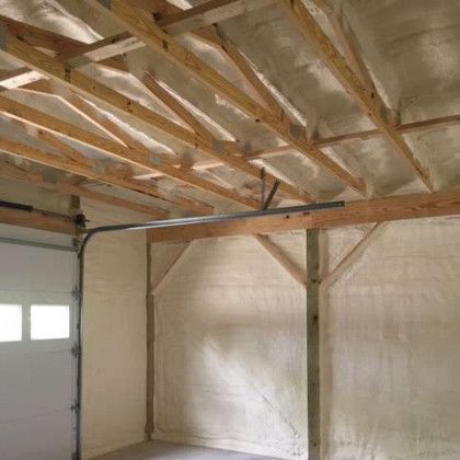 A garage with a garage door and a ceiling covered in spray foam.