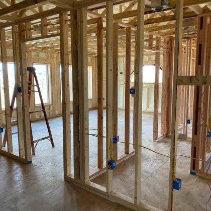 The inside of a house under construction with a ladder in the middle of the room.