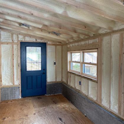 A room with a blue door and windows is being built.