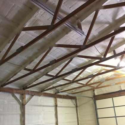 The ceiling of a garage with wooden beams and foam on it.