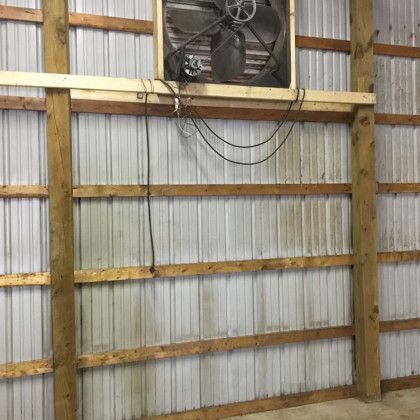 A fan is hanging on the side of a building.