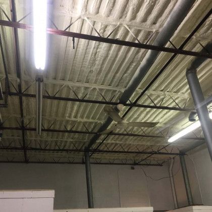 The ceiling of a building with a lot of pipes hanging from it.