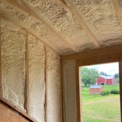 A room with a window and a red barn in the background.