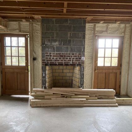 A room with a fireplace and a stack of wood in front of it