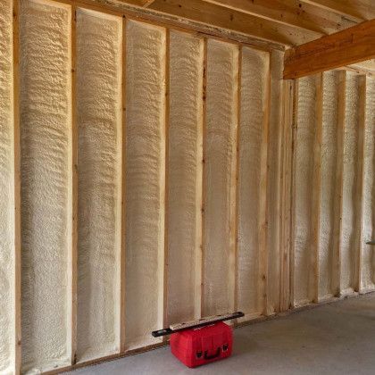 A red cooler is sitting in front of a wall covered in spray foam.