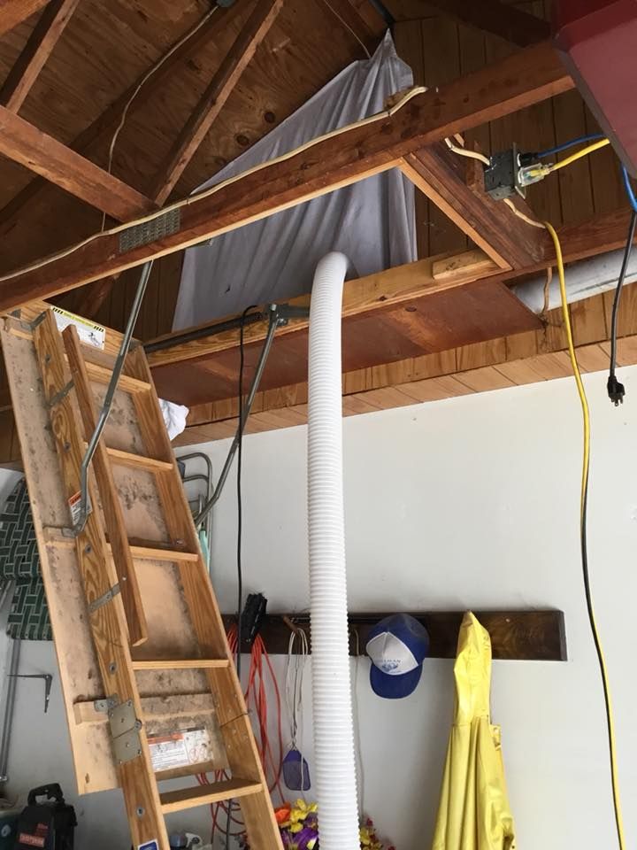 A wooden ladder is hanging from the ceiling of a garage.