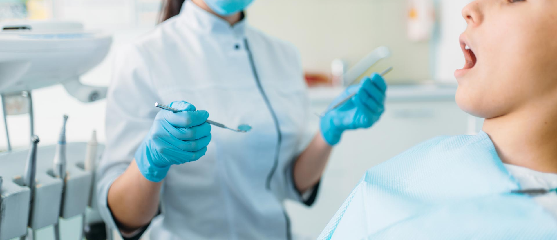 Dental tools, including a tooth, floss, and toothbrush, on a turquoise background.
