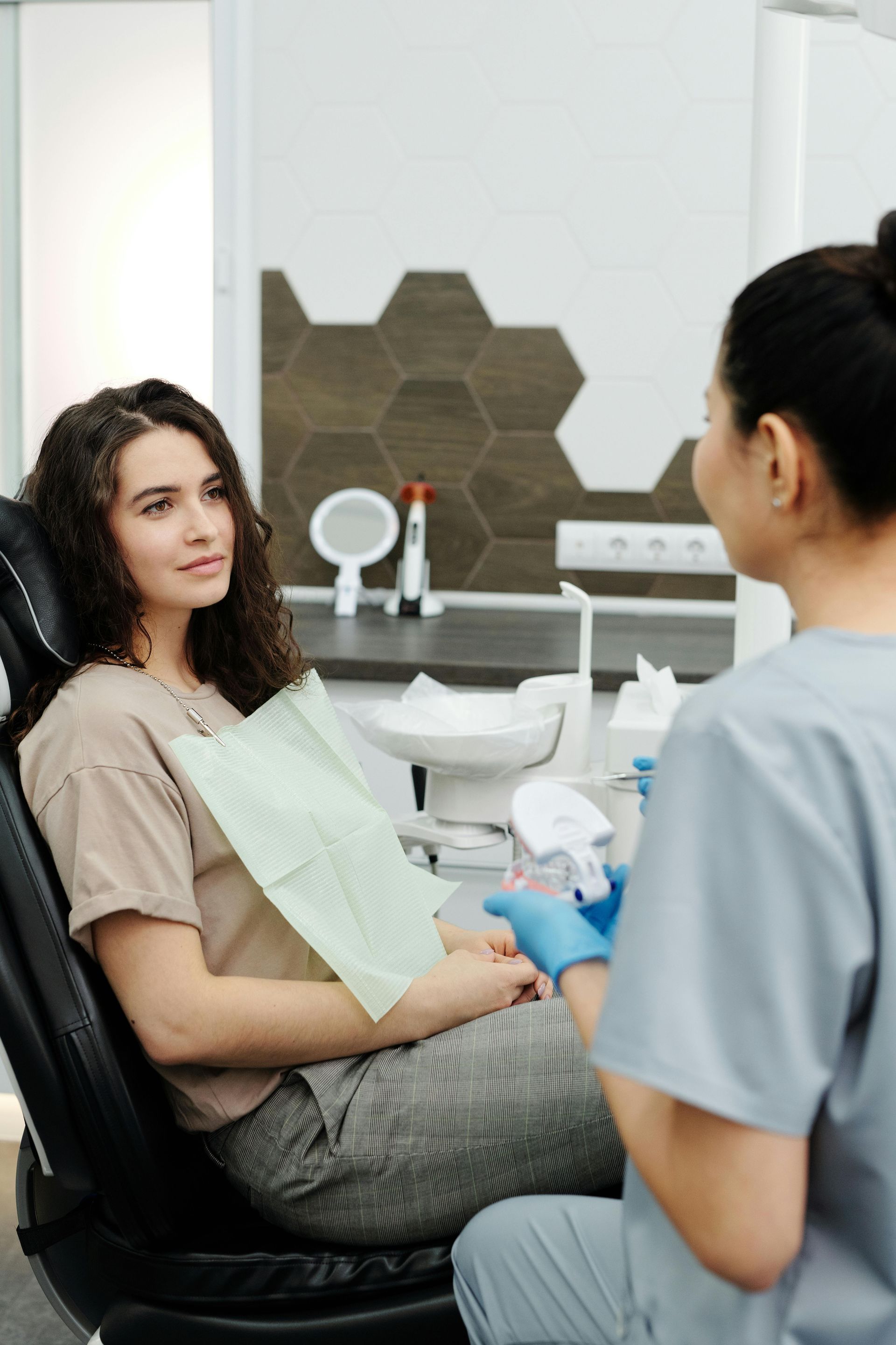 Woman in dental chair talks to a dentist in a modern office.