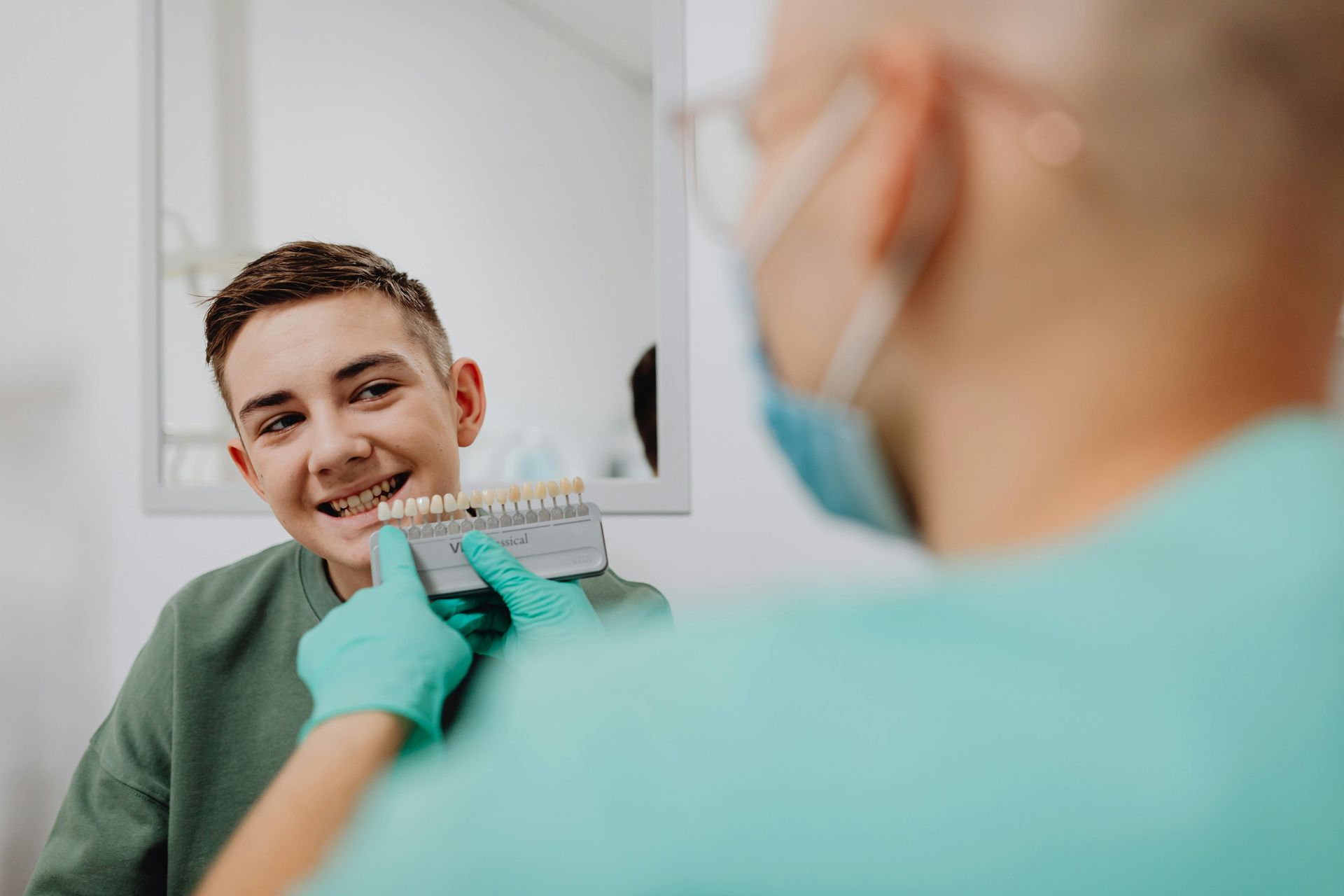 Dentist showing teeth shade guide to a smiling patient in a dental office.