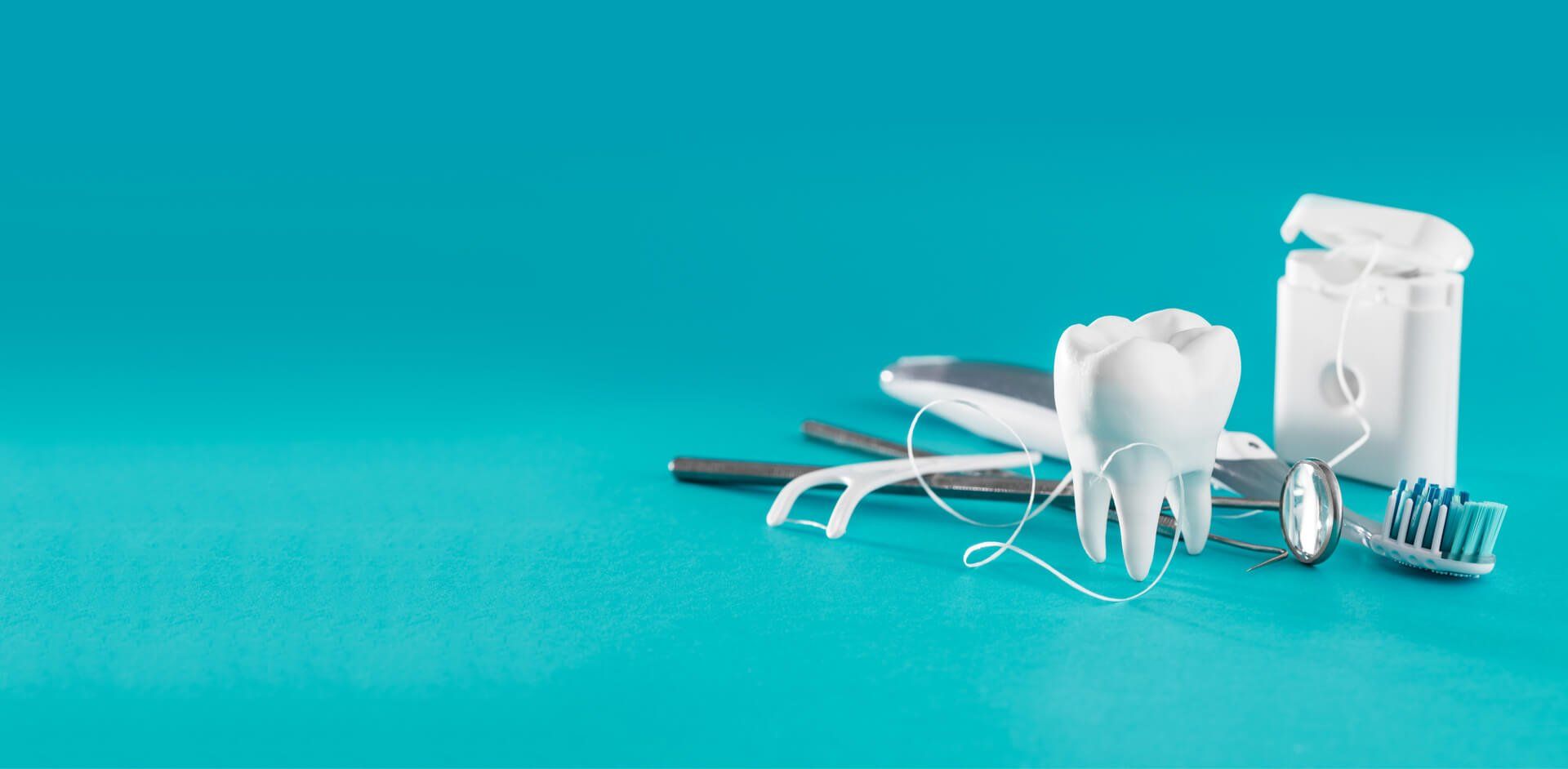 Dental tools, including a tooth, floss, and toothbrush, on a turquoise background.