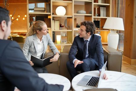 A man and a woman are sitting at a table with a laptop