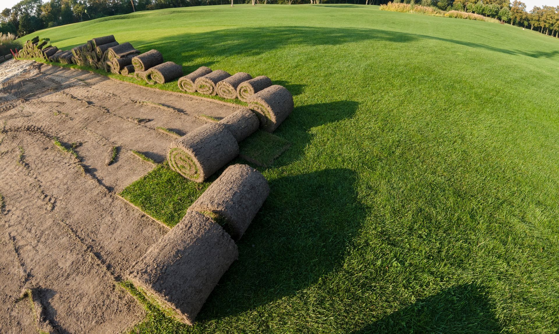 Several rolls of turf are sitting on top of a lush green field