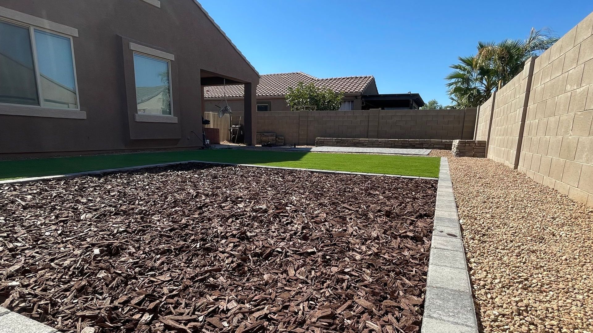 A house with a fence and a pile of mulch in front of it