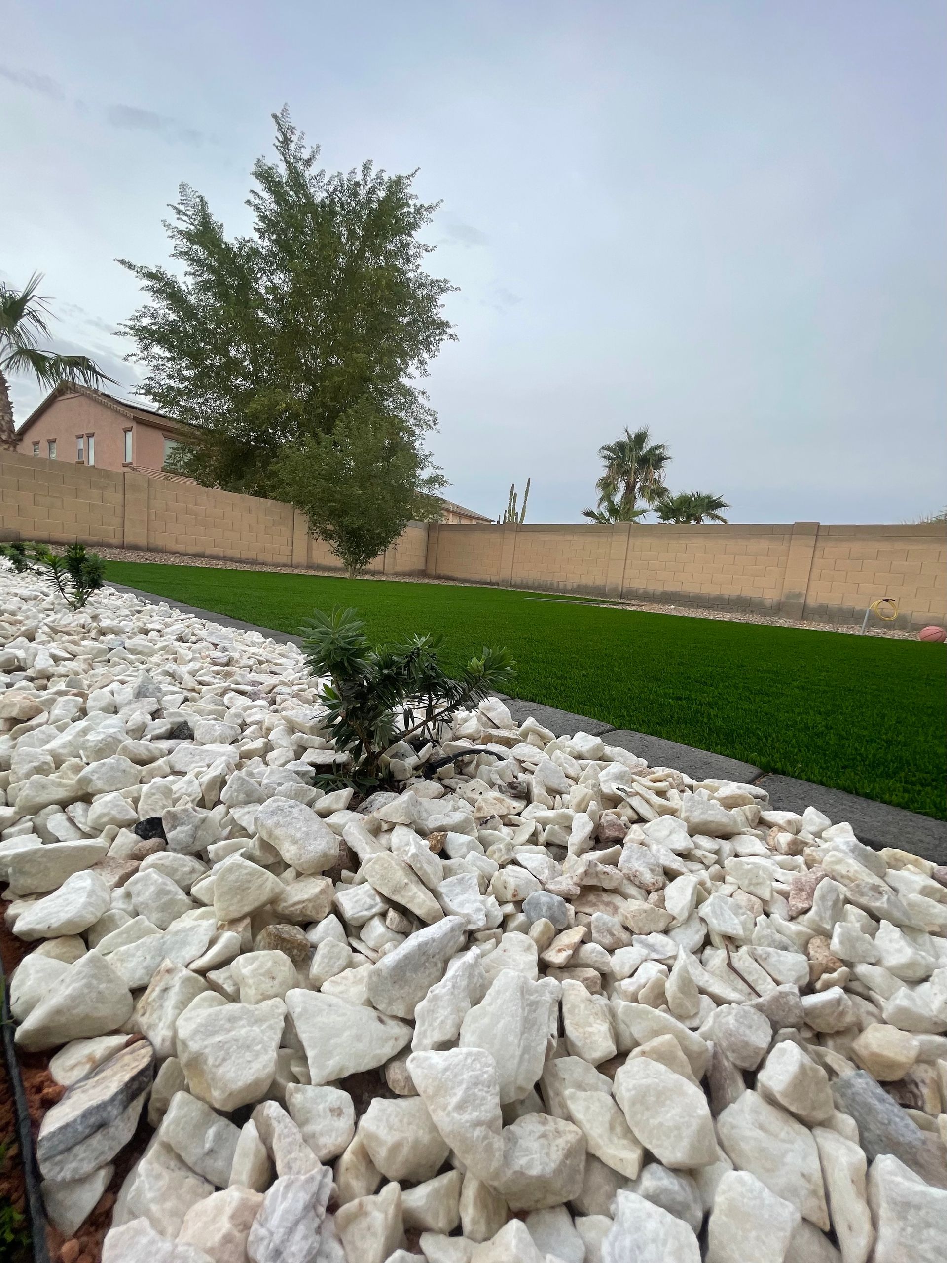 A pile of white rocks sitting next to a lush green lawn.