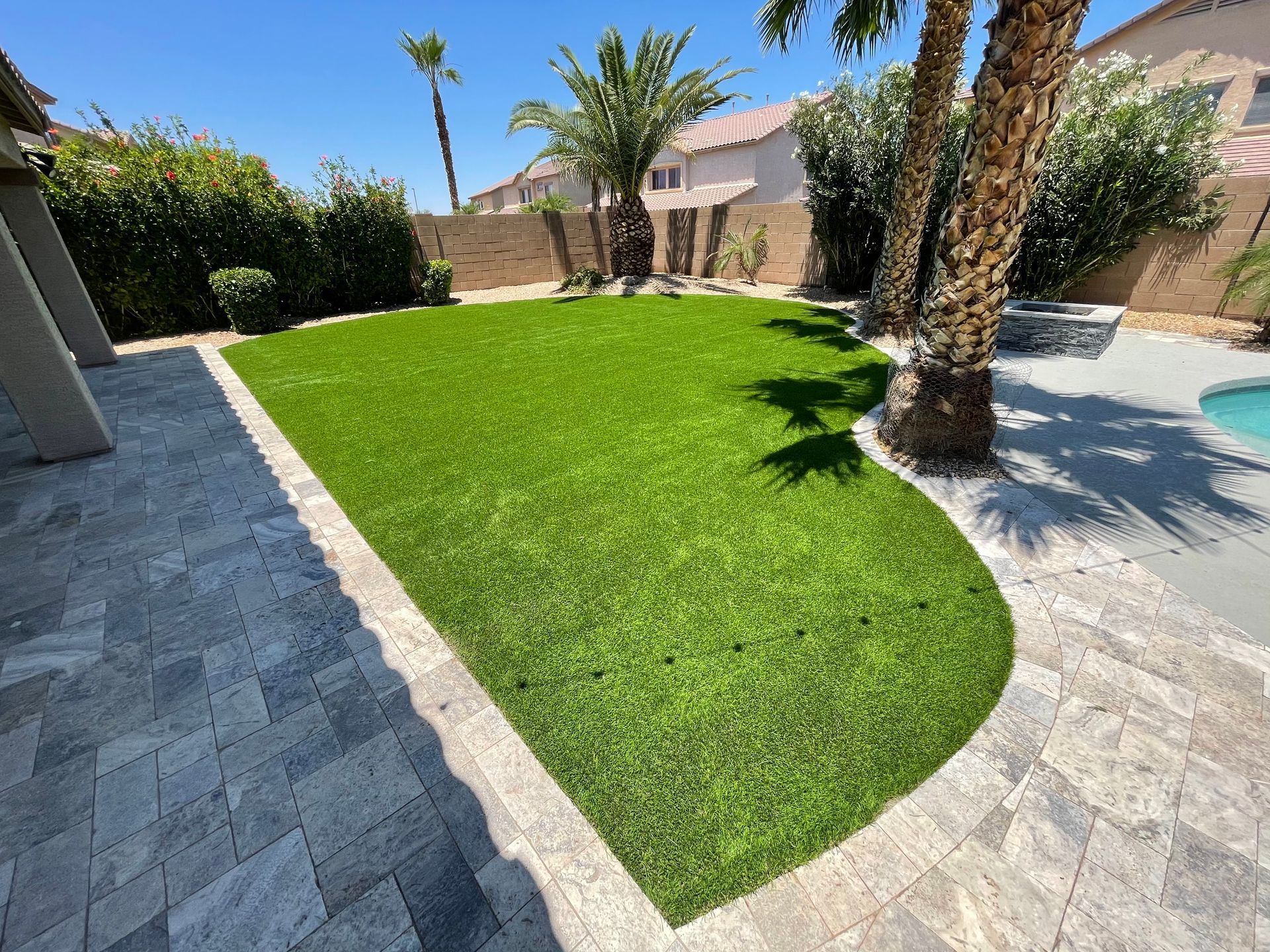 A backyard with a lush green lawn and palm trees.