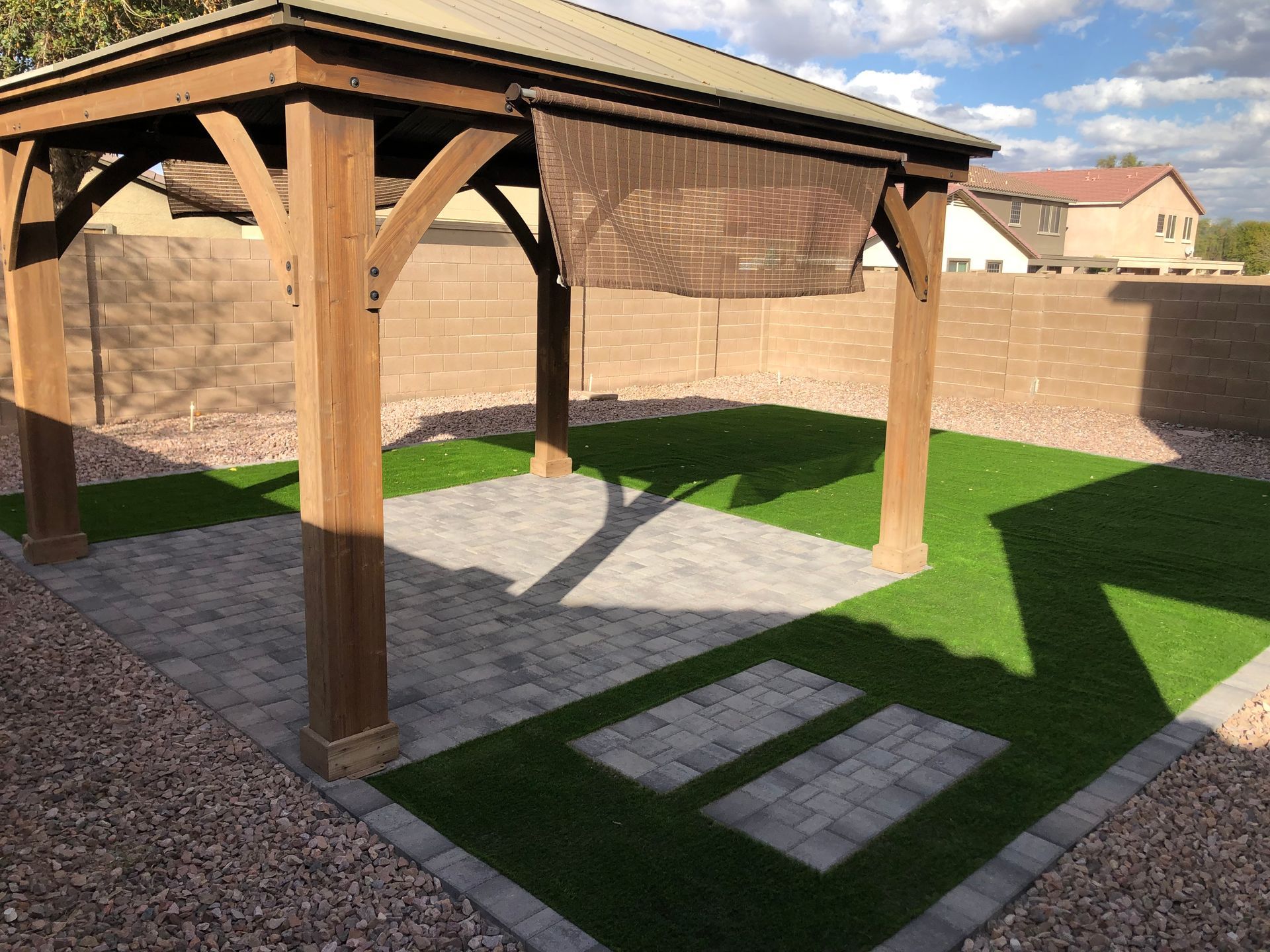 A wooden gazebo is sitting in the middle of a lush green yard.