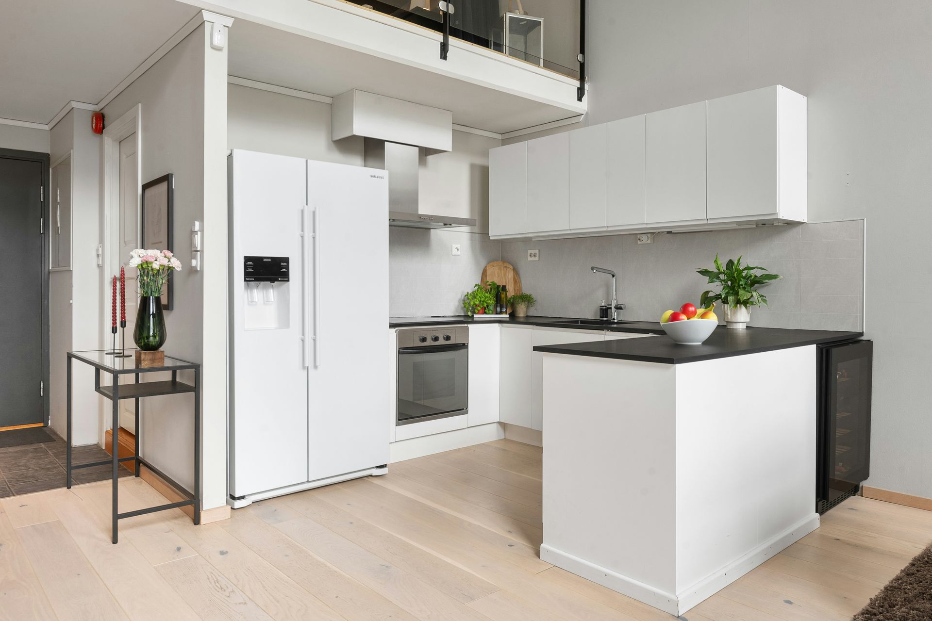Modern white kitchen with a refrigerator, cabinets, and a black countertop island.