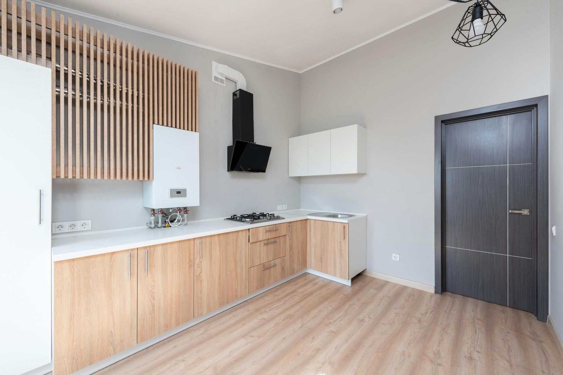 Modern kitchen with light wood cabinets, gray walls, white countertops, and a black range hood.