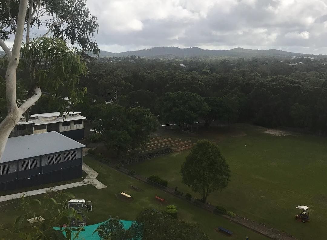 An aerial view of a lush green field with a house in the background.