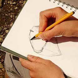 A person drawing with a notebook and a pencil