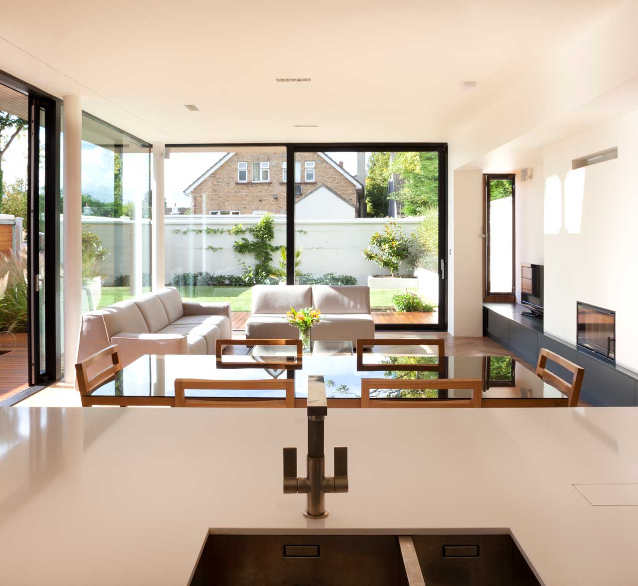 View from the kitchen of the dinning table and the living room located at Hazel lane, County Dublin designed by 'Dublin Design Studio'