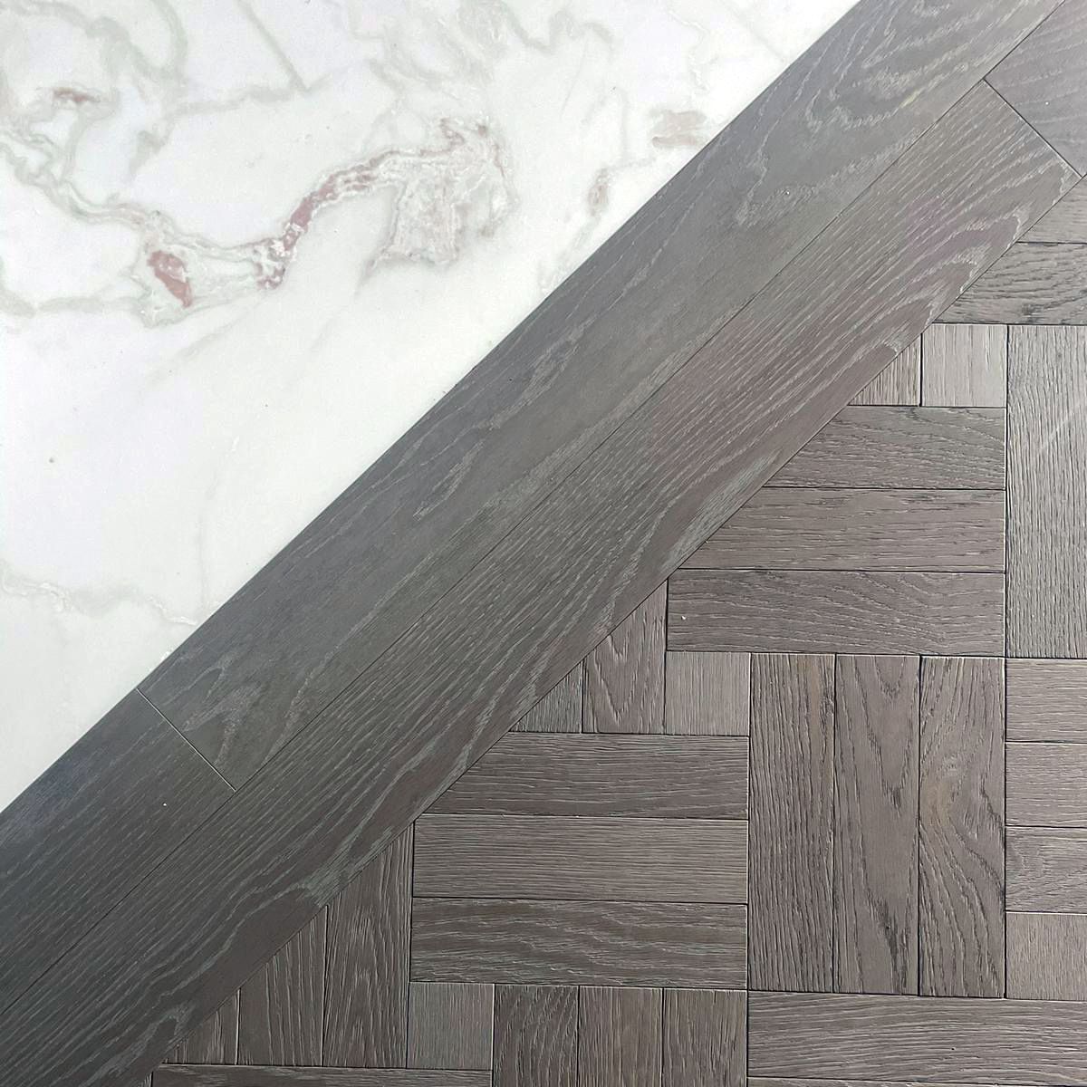 A close up of a wooden floor next to a marble floor.