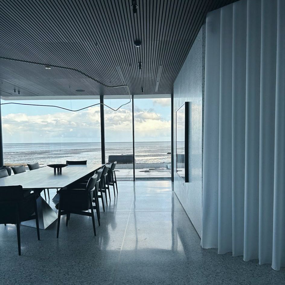 A dining room with a table and chairs and a view of the ocean