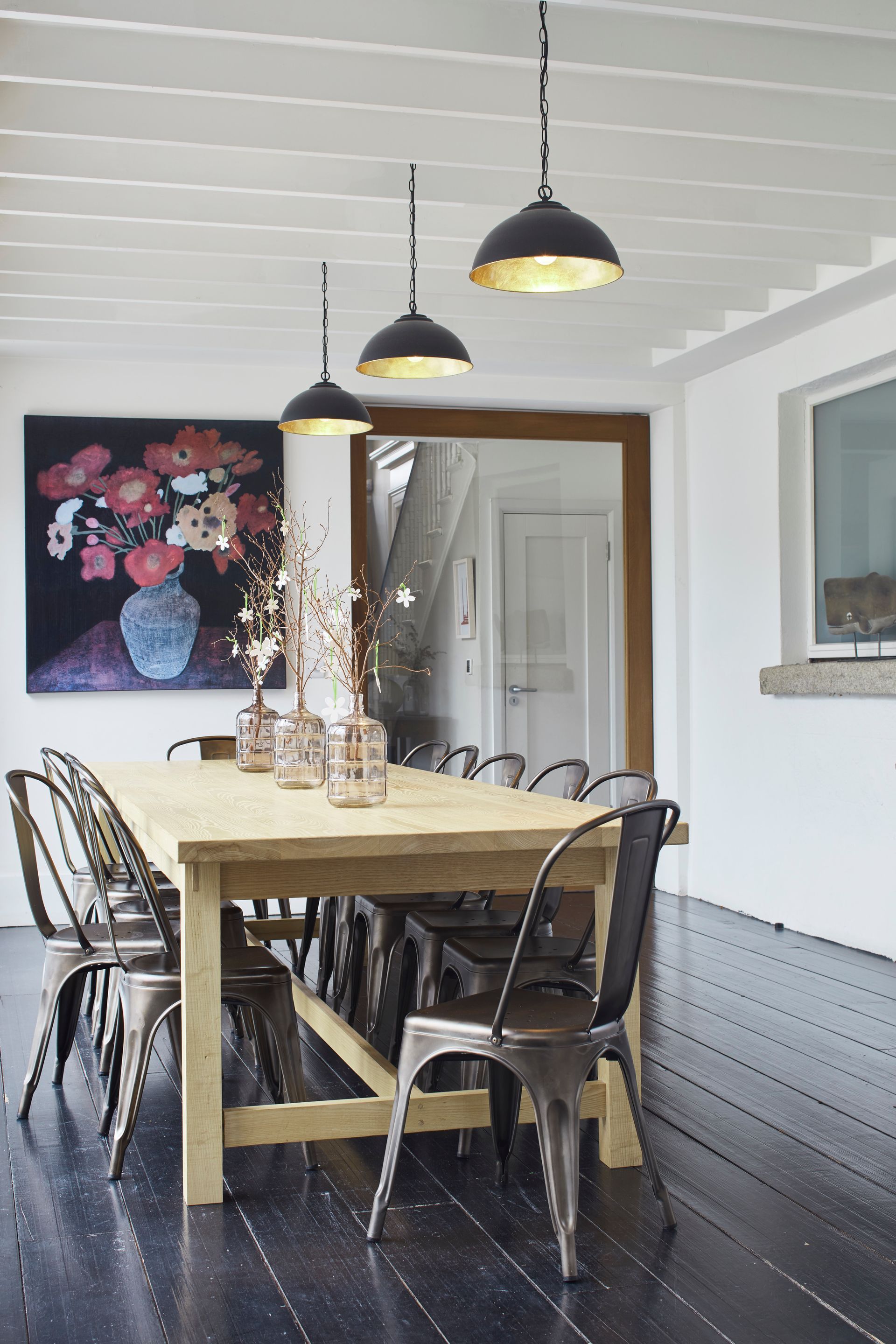 A dining room with a table and chairs and a painting on the wall