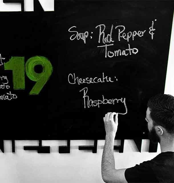Green 19 restaurant menu on a blackboard with a server writing down the offered meals