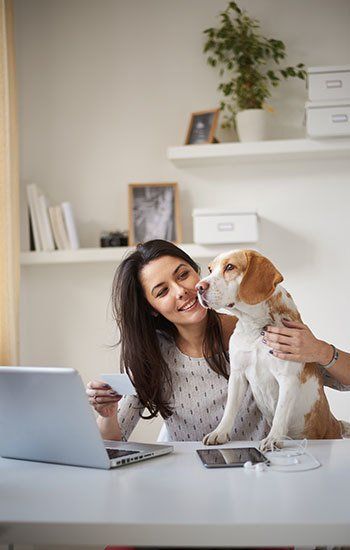 businesswoman sitting in home office with her dog