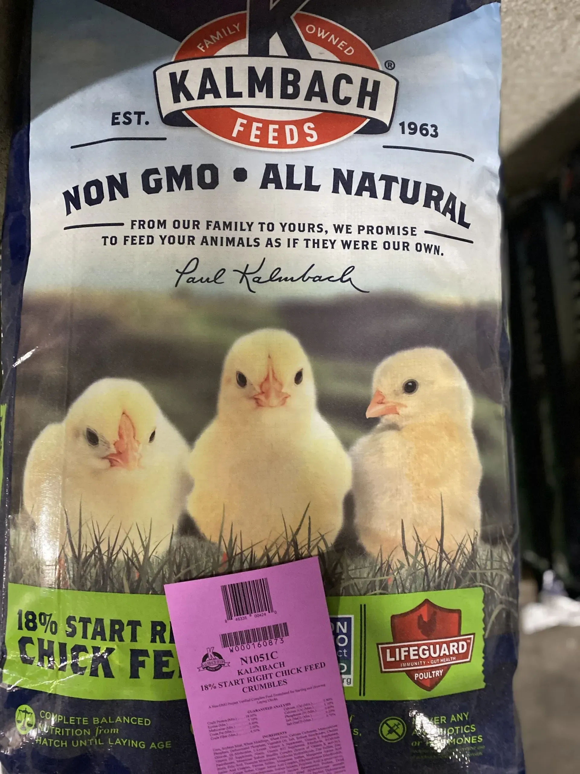 A bag of kalmbach feeds with three chicks on it