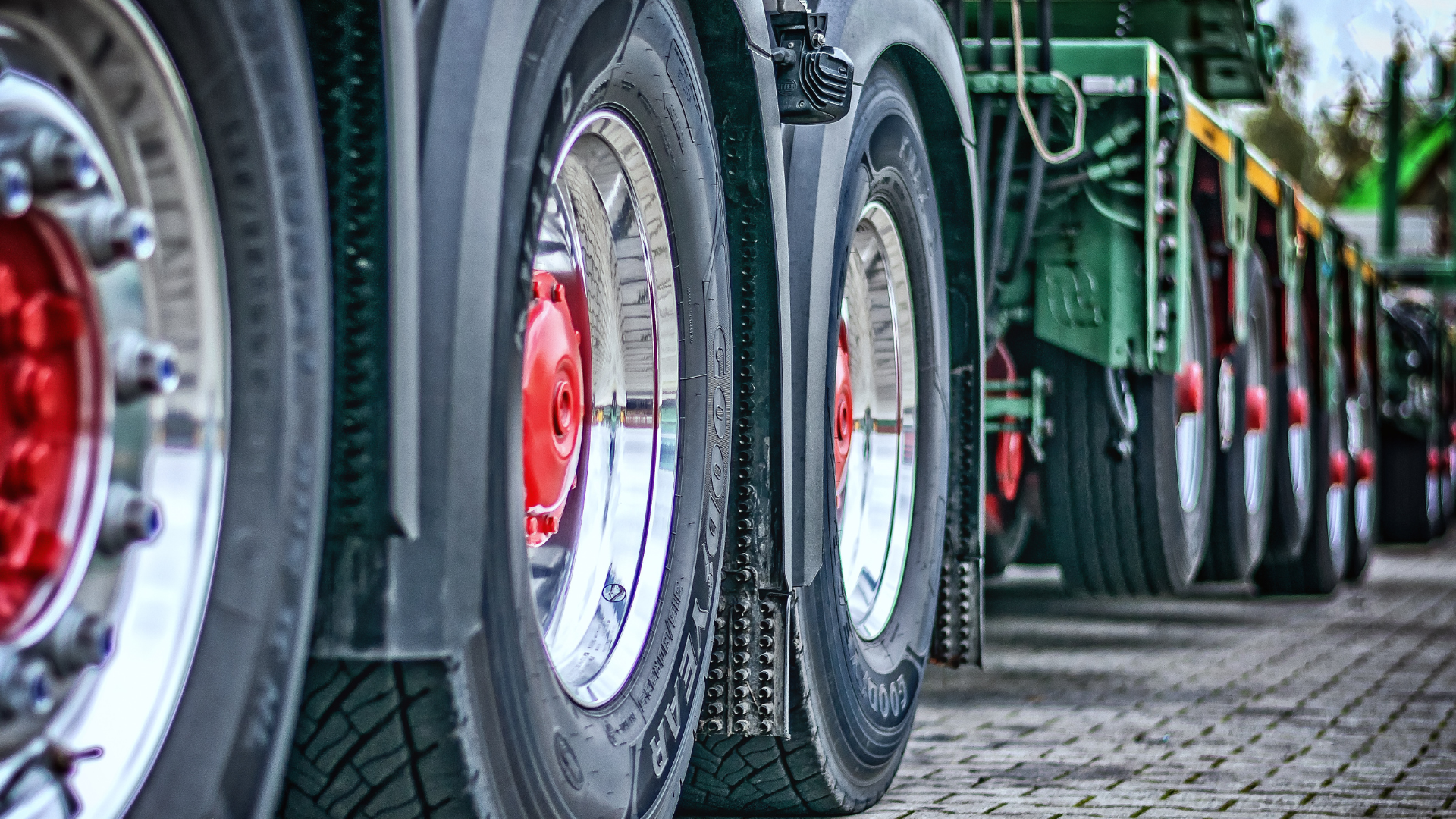 A row of semi trucks parked next to each other on a brick road.